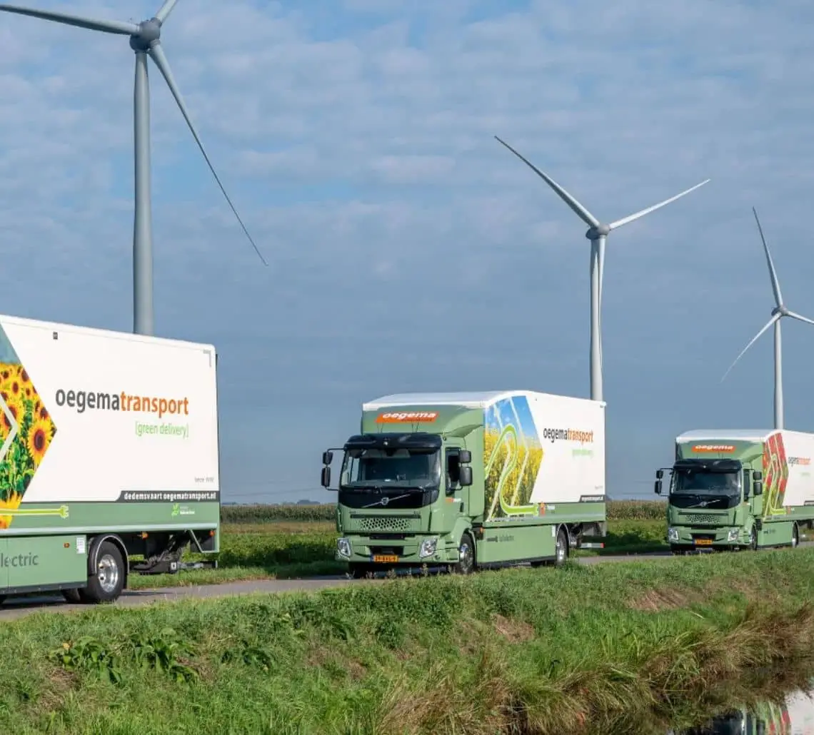 Oegema Transport truck powered by locally generated green energy with visible solar and wind energy sources in the background.